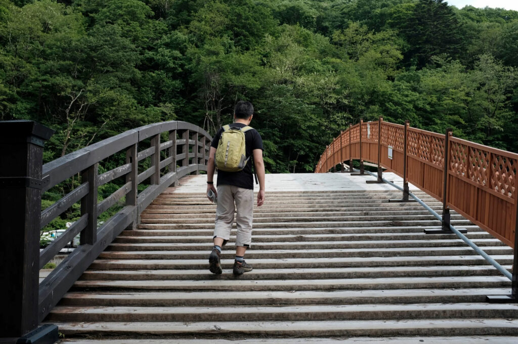 Man walking over wooden bridge away from camera